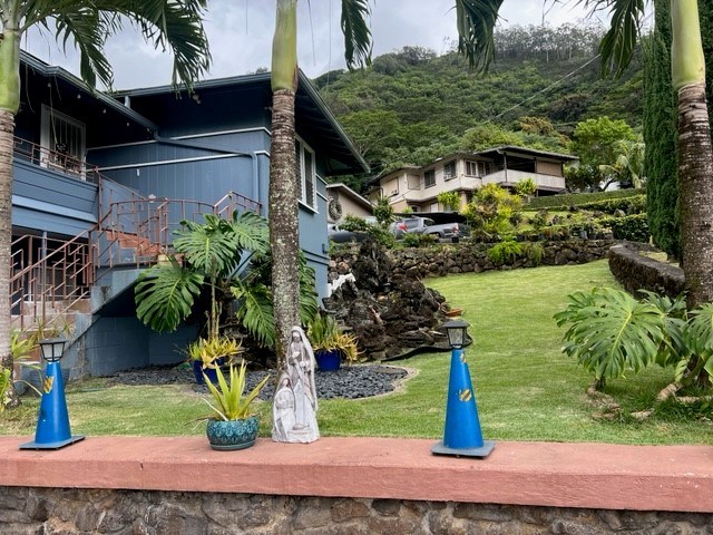 A blue house with a green lawn and trees.
